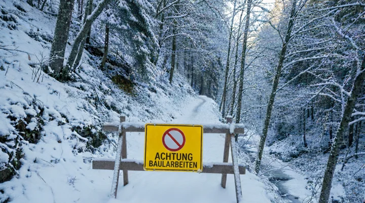 KI generierter Inhalt | © 2025, DAV Friedrichshafen  Die Szene zeigt eine Absperrung mit einem Baustellenschild, dass einen Wanderweg im Wald im Winter versperrt. | © 2025, DAV Friedrichshafen