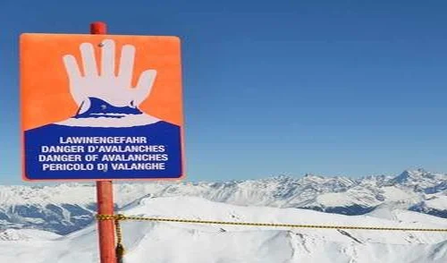 Lawinenlagebericht | © DAV Lawinenwarnschild an einer Pistebegrenzung vor winterlichem Bergpanorama | © DAV